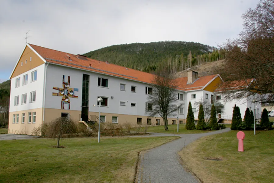 Ein stor bygning med ein plen framfor seg